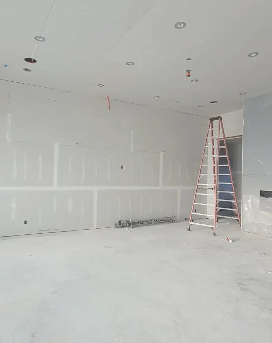 Room under renovation with ladder and drywall.