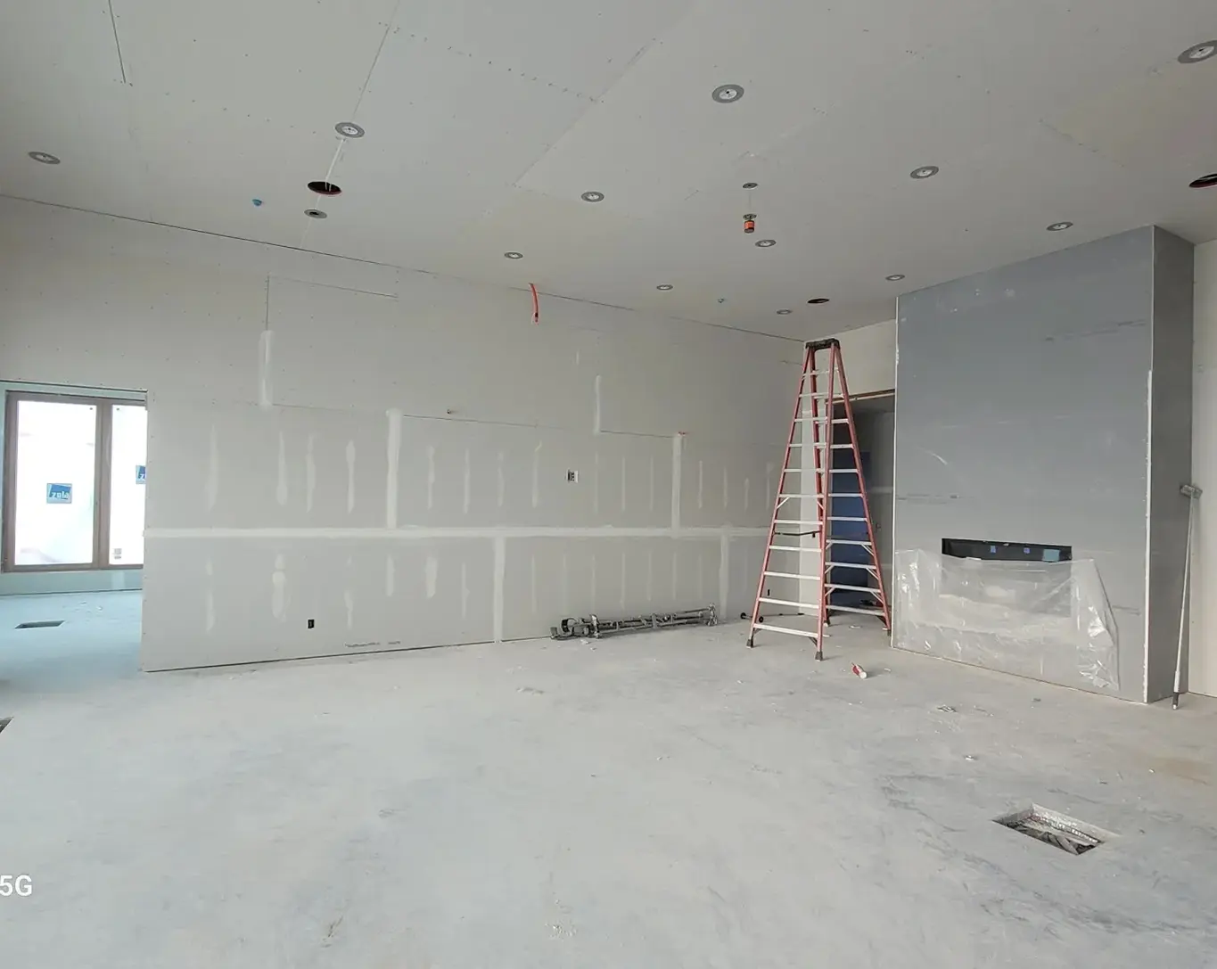 Unfinished room with ladder and drywall.