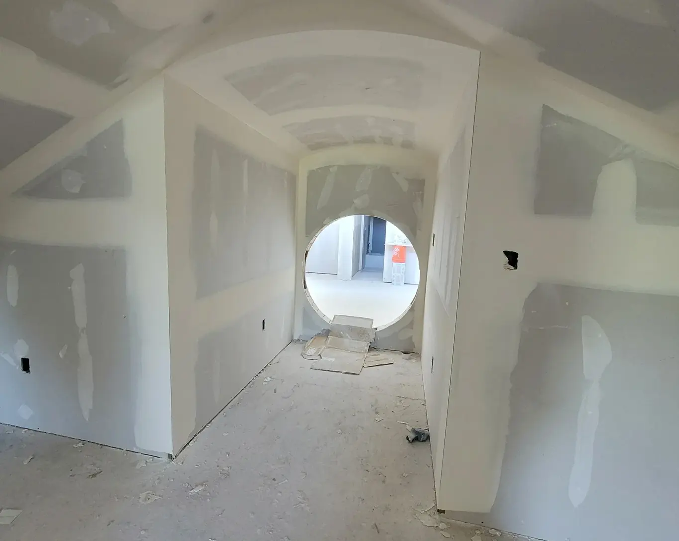 Unfinished room with circular opening, drywall installed.