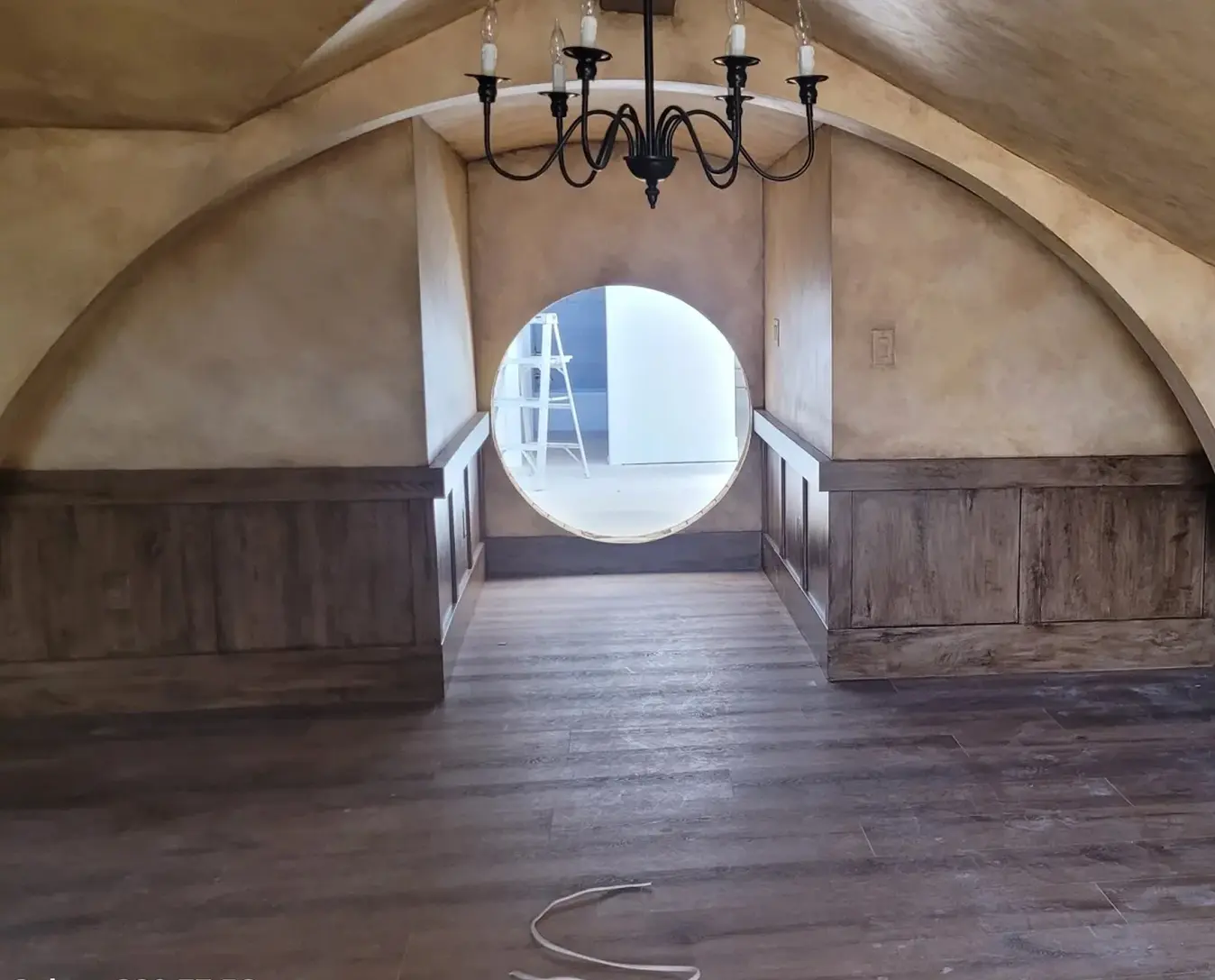 Rustic attic with chandelier and round window.