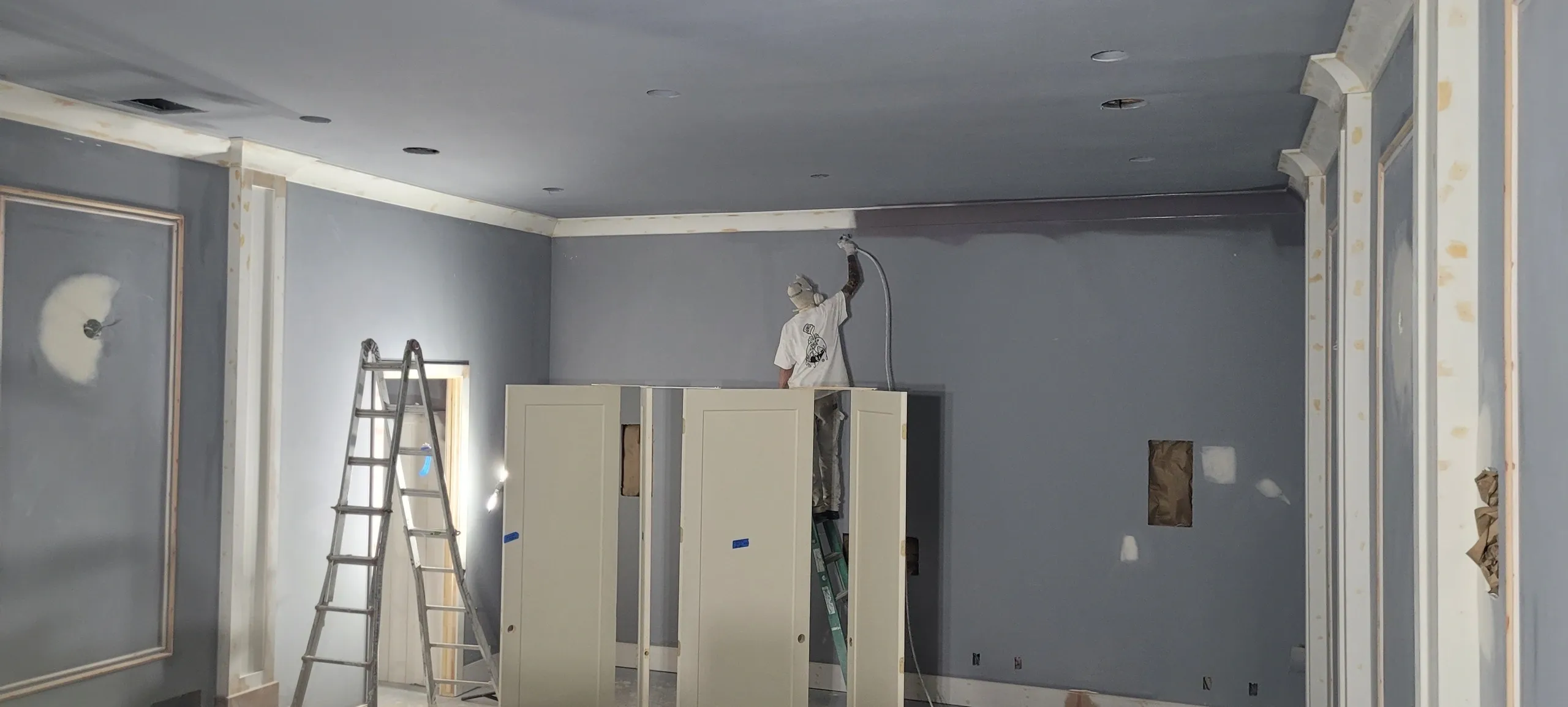 Room being painted with ladder and cabinets.