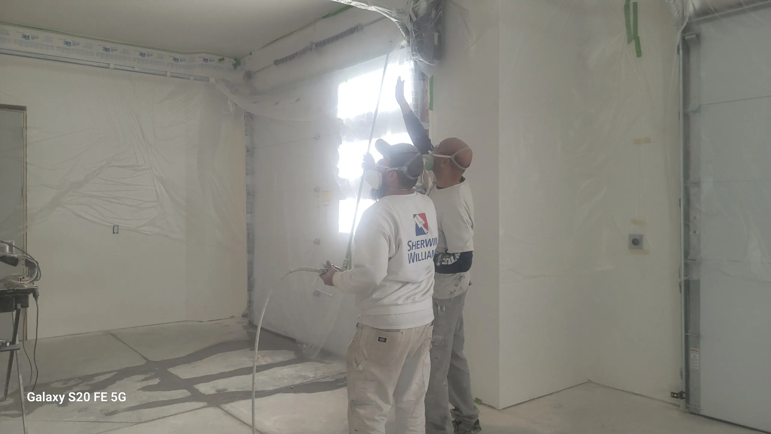 Two workers painting a garage interior.