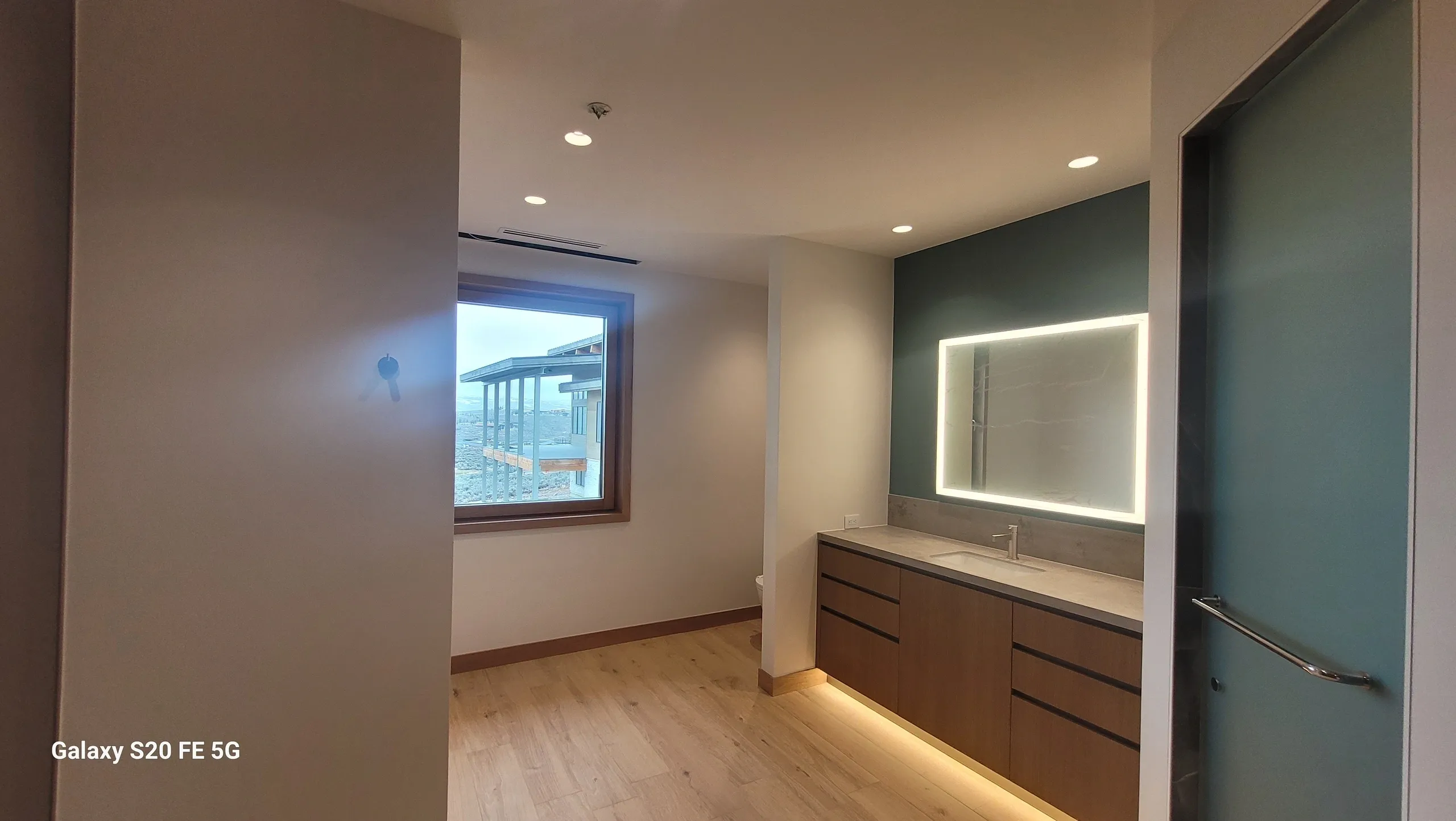 Modern bathroom with mirror and window view.