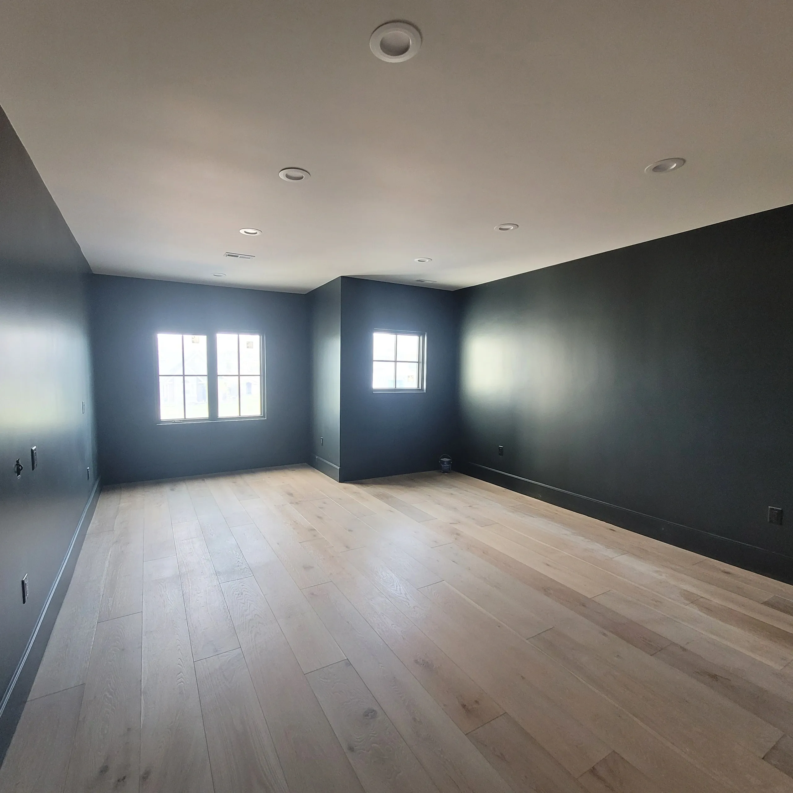Empty room with wooden floor and windows.