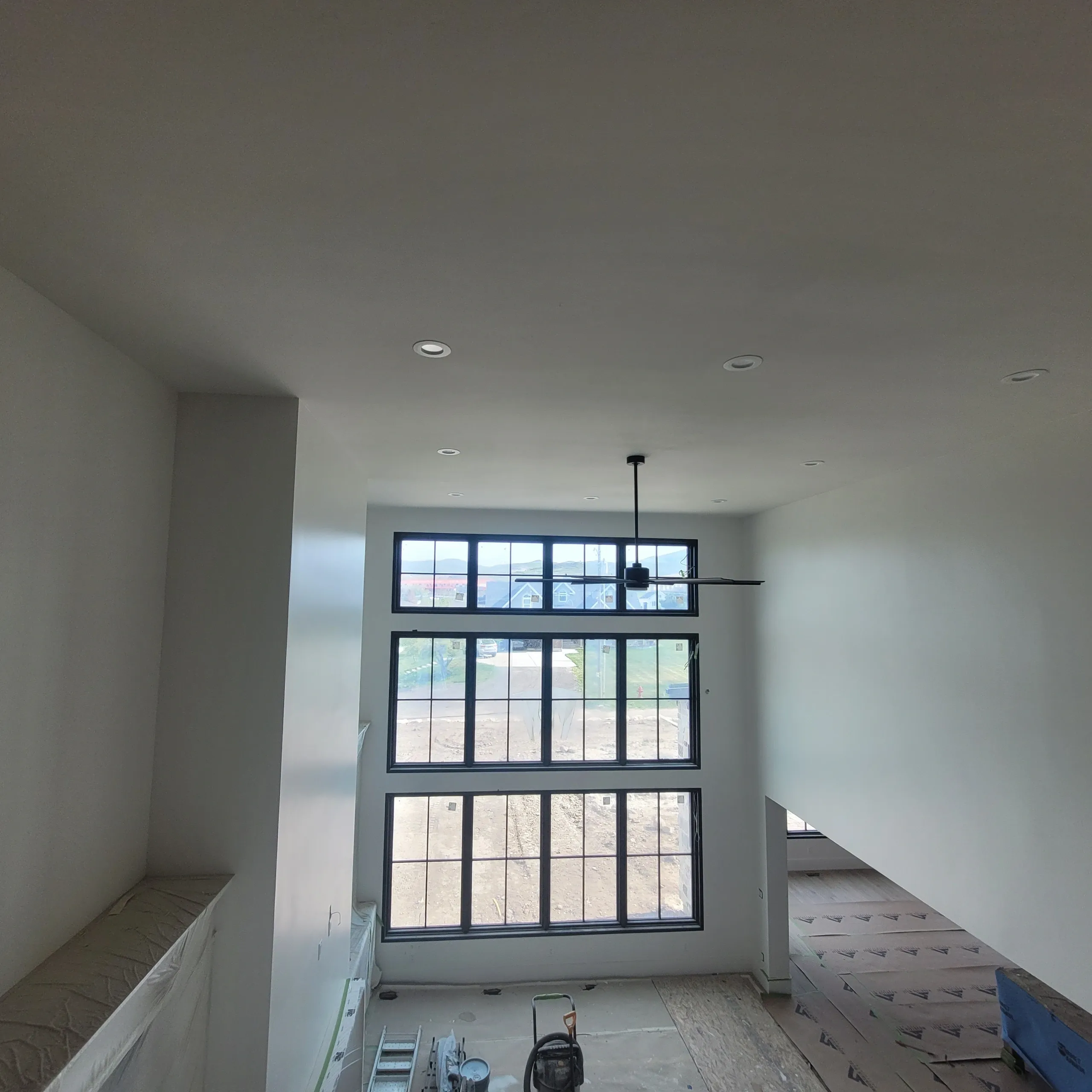 Modern room with large windows and fan.